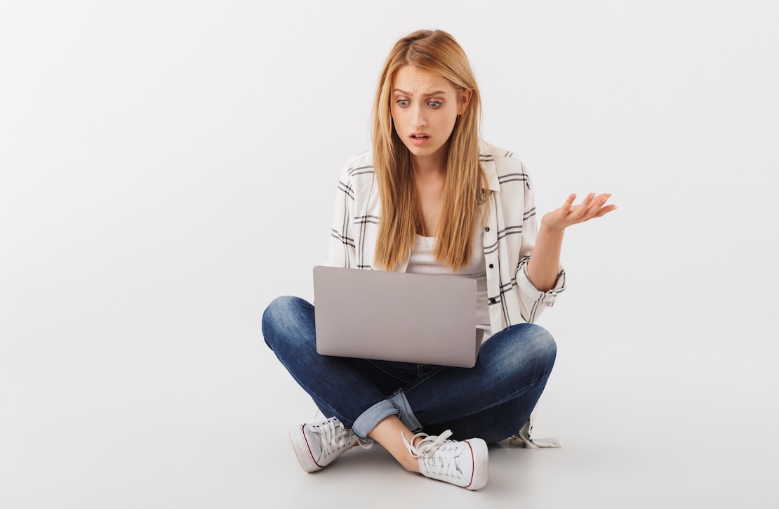 Girl sitting cross-legged with a computer, looking confused